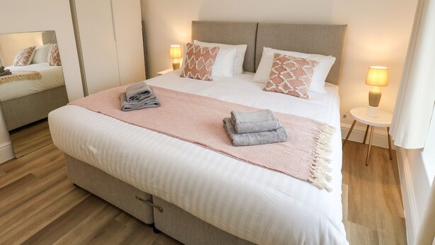 A modern hotel room with a large bed, bedside lamps, and a wardrobe. - Alma Cottage (Buxton)
