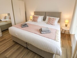 Una camera d'albergo moderna con un letto grande, lampade sui comodini e un armadio.