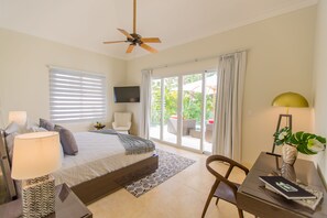 A bedroom with a bed, a desk, a chair, a ceiling fan, a TV, and a view of the outdoors. - Luxury The Dream villa w/golf view, outdoor screen movie, CHEF & staff incl. (Punta Cana)