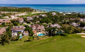 An aerial view of a coastal residential area with houses, a golf course, and a swimming pool. - Luxury The Dream villa w/golf view, outdoor screen movie, CHEF & staff incl. (Punta Cana)