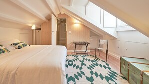 Un dormitorio con una cama grande, un banco, una silla y una maleta.