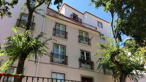 Un edificio de varios pisos con balcones, ventanas y una entrada protegida por una reja.