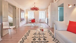 Una sala de estar moderna con un sofá blanco, cojines rojos, una mesa de centro y una alfombra estampada.