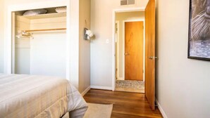 Een slaapkamer met een bed, een kast en een deur naar een andere kamer.