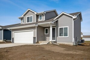 Situated in a residential area, this two-story home features a symmetrical facade with a garage door and small front porch.