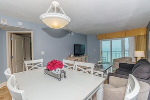 Relax in a comfortable living space with a dining table, sofa, and TV, perfect for leisure and entertainment.