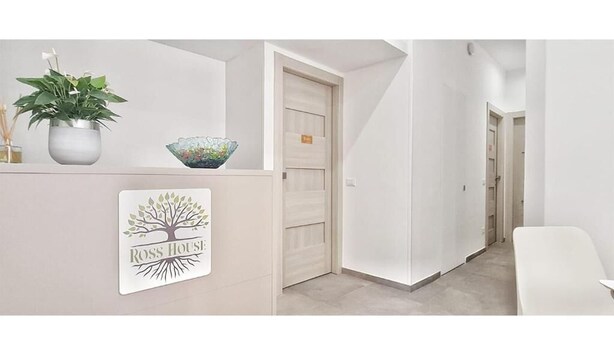 Zona de recepción con un mostrador blanco, una planta en maceta, un cuenco decorativo y un cartel que dice "Ross House".