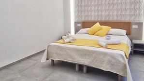 Un dormitorio moderno con cama, cabecera con panel texturizado e iluminación empotrada en el techo.