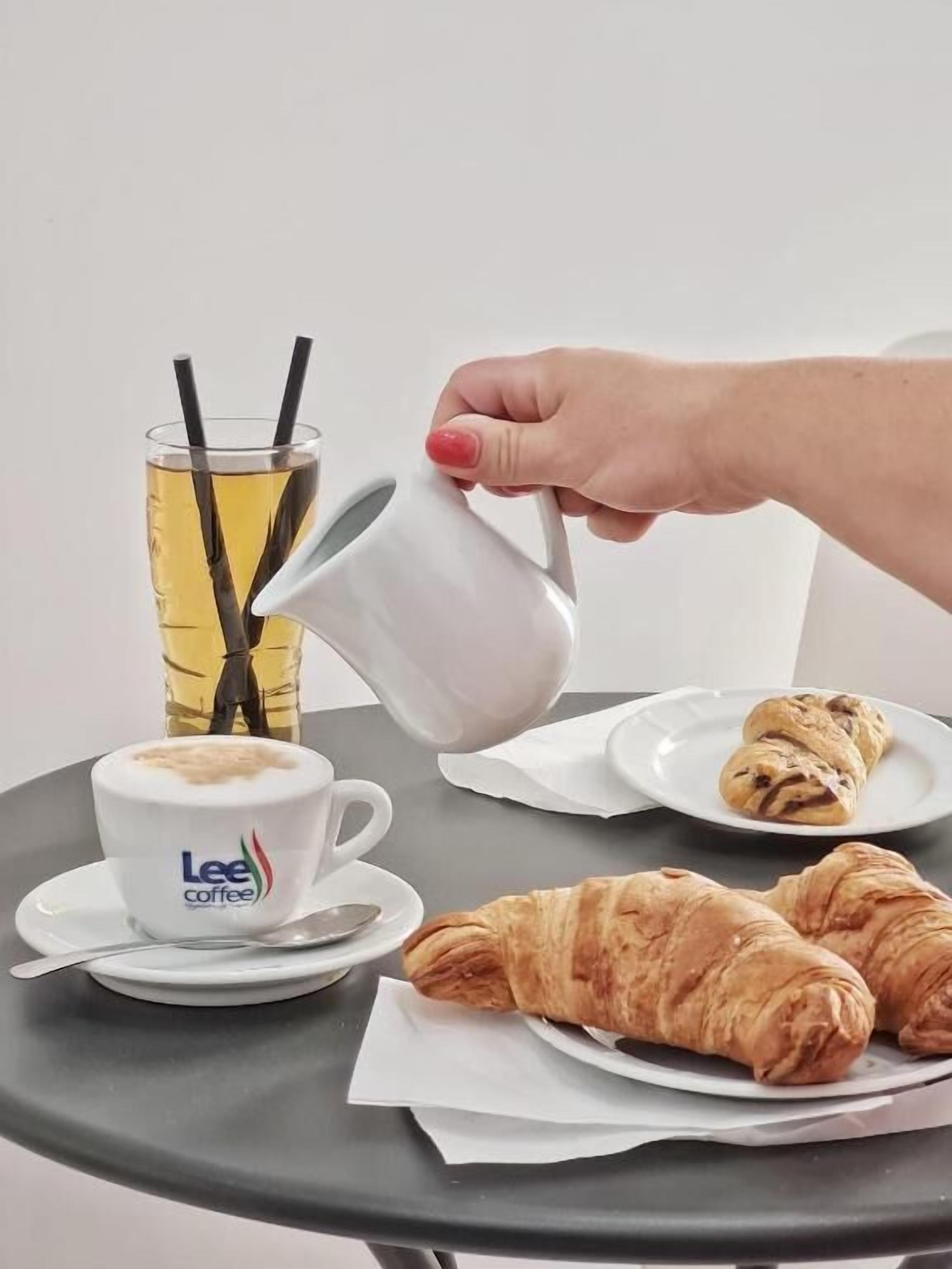 Une table avec une tasse de café, un verre de thé et des croissants.