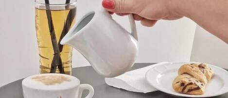 Une table avec une tasse de café, un verre de thé et des croissants.