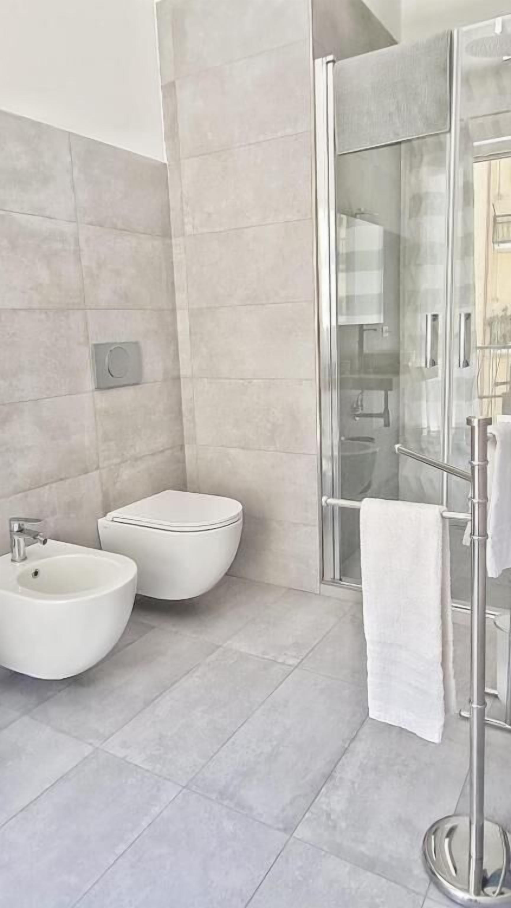 Un baño moderno con mampara de vidrio, un bidé y un inodoro.