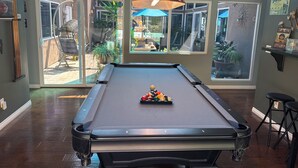 A pool table with a cue ball and rack of billiard balls, a red Budweiser lamp, and large windows offering a view of the outdoors. - Pool & Oceanview, Spacious 4bdrm 2 1/2 ba in a very nice neighborhood. (San Diego)