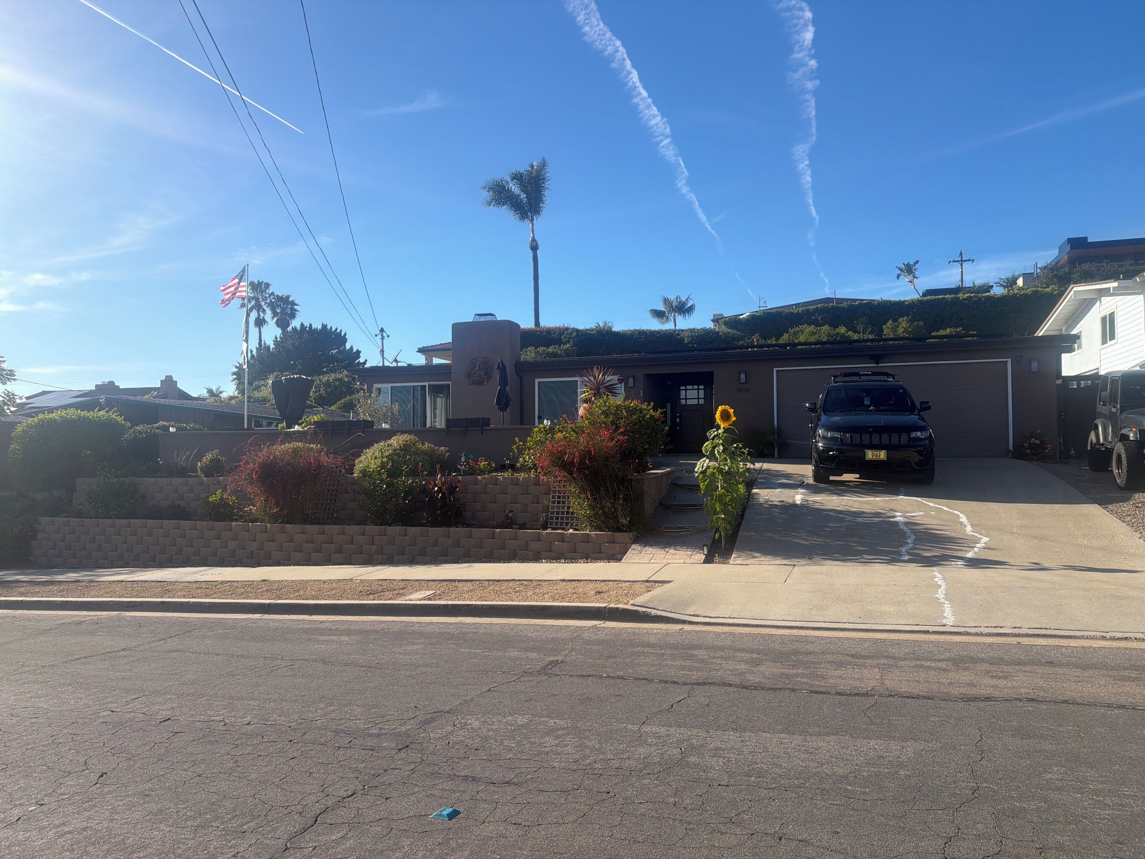 A residential driveway with a parked SUV, a house with a garage, and a clear sky.