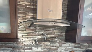 A kitchen with a gas stove, a stainless steel range hood, and a backsplash made of variously colored tiles. - Pool & Oceanview, Spacious 4bdrm 2 1/2 ba in a very nice neighborhood. (San Diego)