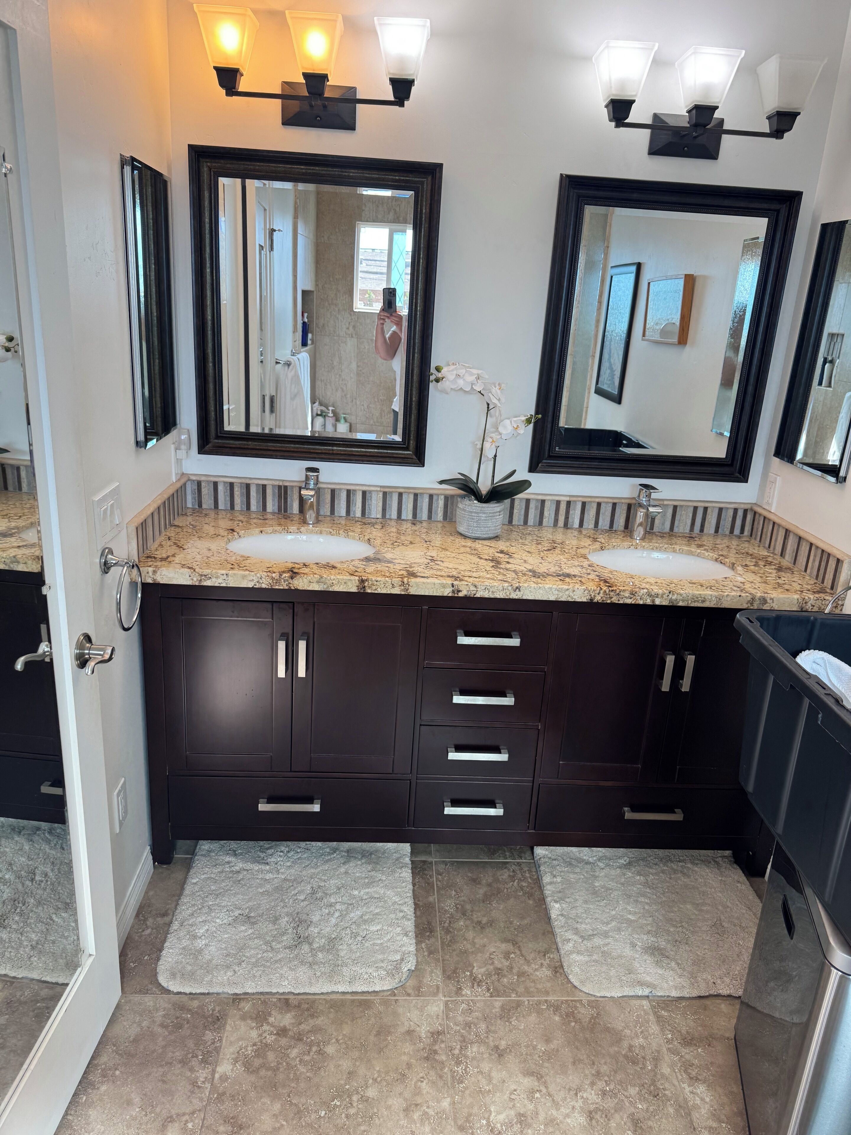 A bathroom with two sinks, dark cabinets, and a mirror.