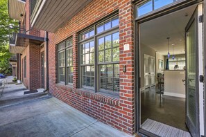 Enter a contemporary space with a glass door leading to a well-lit interior and a kitchen area.