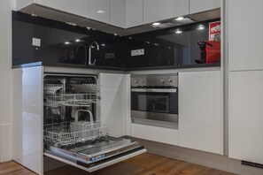 A modern kitchen with a dishwasher, oven, and stainless steel appliances.
