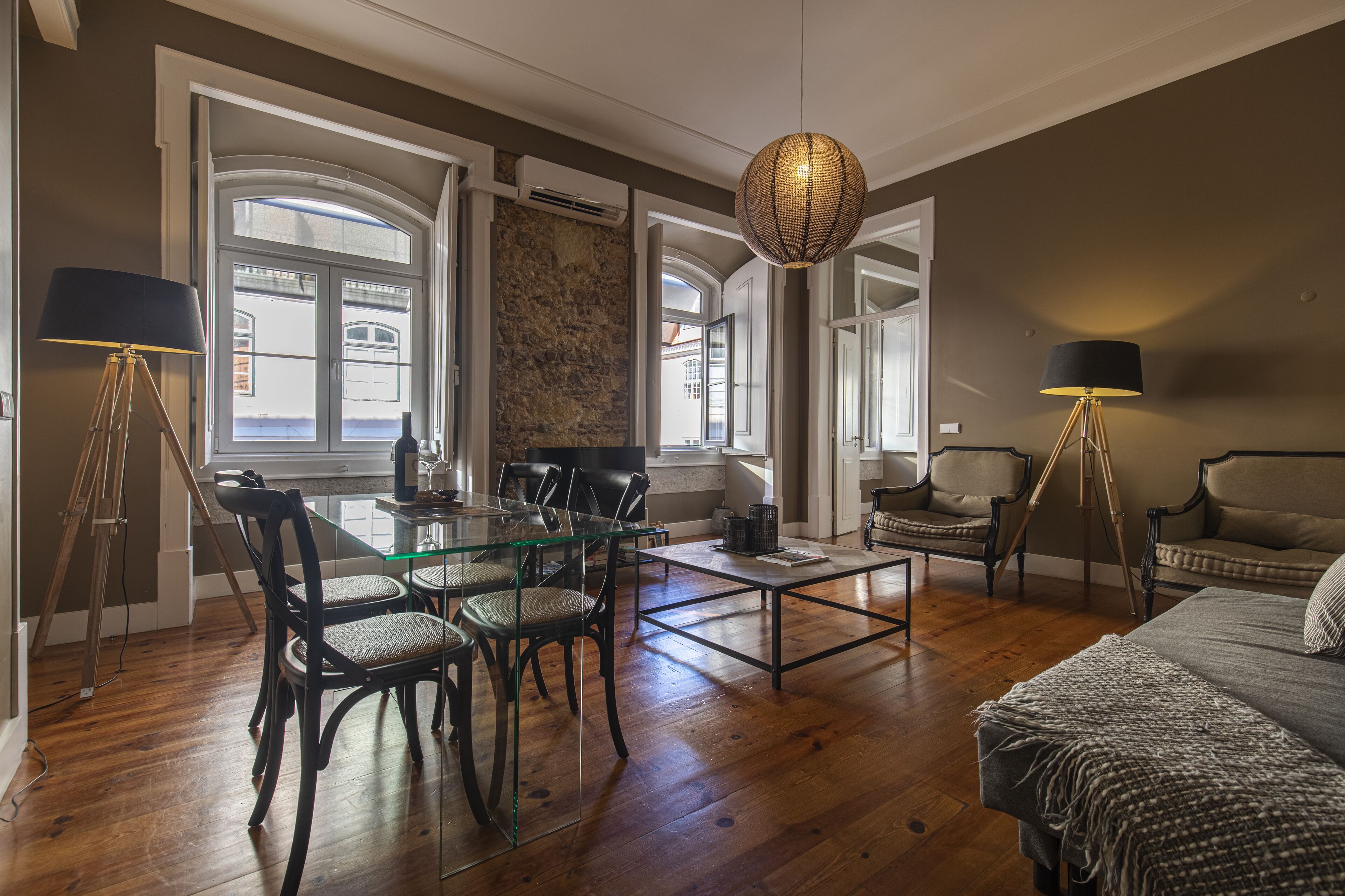 A spacious living area with a glass dining table, comfortable seating, a large window, and a cozy sofa.