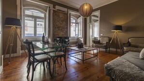 A spacious living area with a glass dining table, comfortable seating, a large window, and a cozy sofa. - Central São Paulo by Lisbon Heart (Lisboa)