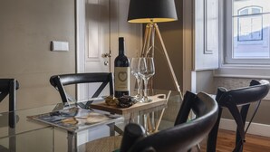 A dining table with a magazine, a bottle of wine, and glasses, set in a room with a lamp and chairs. - Central São Paulo by Lisbon Heart (Lisboa)