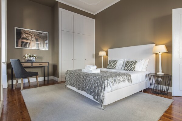 A bedroom with a bed, bedside tables, a desk, and a chair.