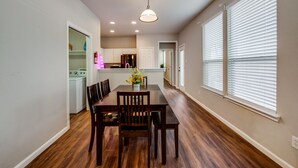A dining area with a wooden table and chairs, a pendant light, and a view of the kitchen in the background. - Spacious & Comfortable 3 Bedroom Home with Garage (Fort Worth)