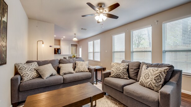 A spacious living room with two grey sofas, a wooden coffee table, and a ceiling fan. - Spacious & Comfortable 3 Bedroom Home with Garage (Fort Worth)