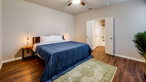 A bedroom with a bed, a nightstand, a ceiling fan, a door, and a plant. - Spacious & Comfortable 3 Bedroom Home with Garage (Fort Worth)