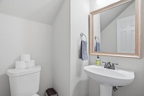 A bathroom with a toilet, sink, and mirror. - Spacious & Comfortable 3 Bedroom Home with Garage (Fort Worth)