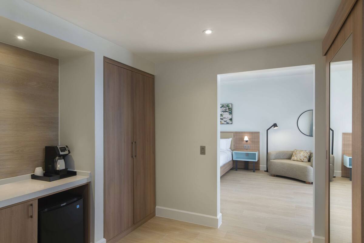 Une chambre d’hôtel moderne équipée d’une kitchenette, d’un lit, d’une table de chevet et d’un canapé.