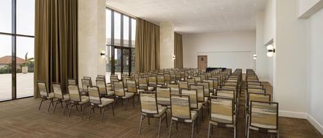 A conference room with rows of chairs, large windows, and a view of the outdoors.