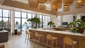 Een moderne keuken met een groot eiland, barstoelen en hangende rieten kroonluchters.