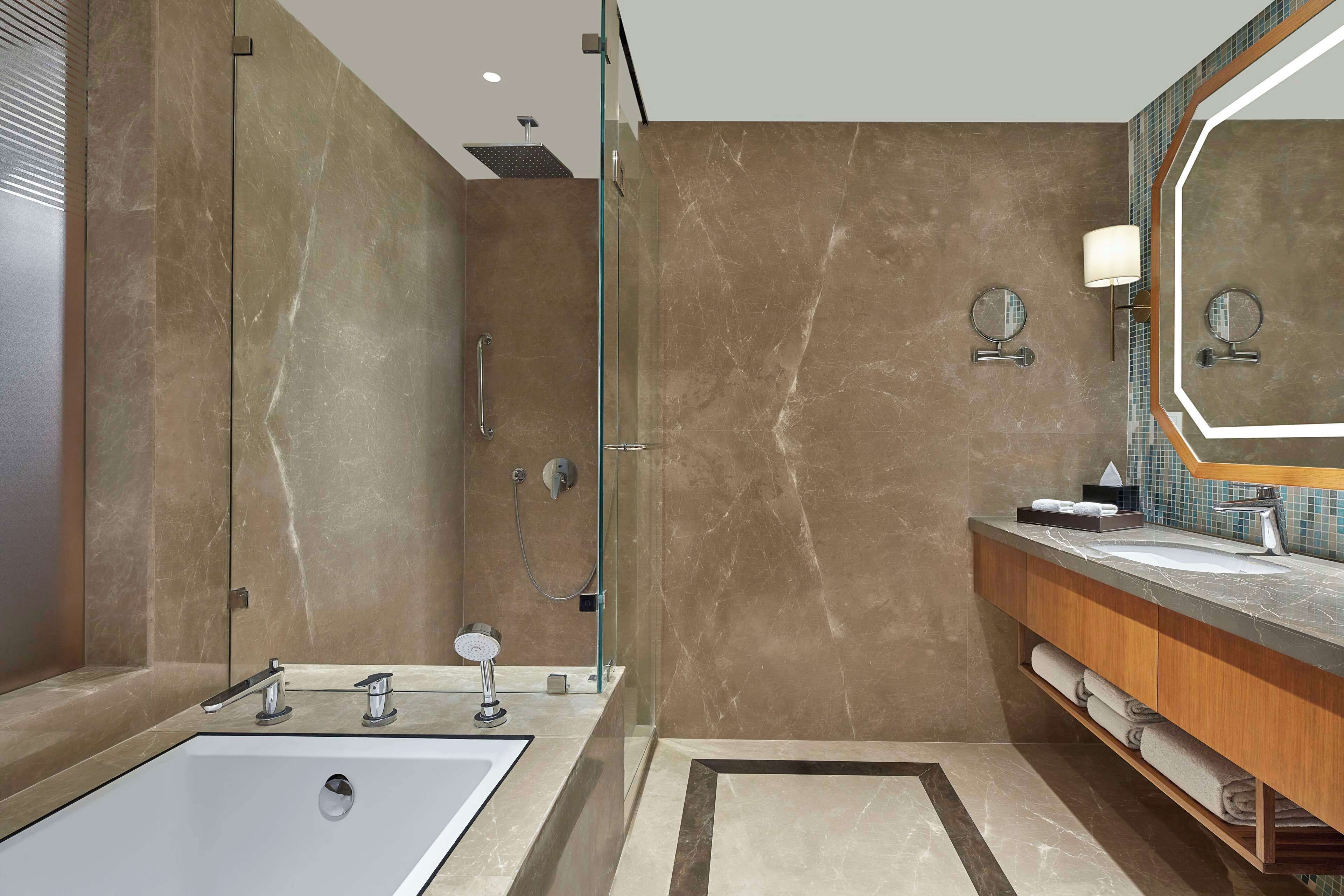 A modern bathroom with a large mirror, a sink, and a shower.