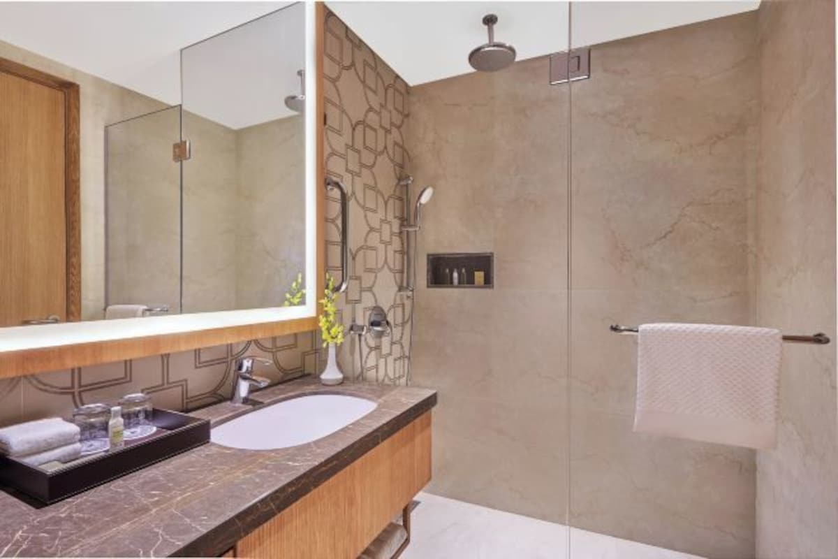 Un baño moderno con un espejo grande, un lavamanos y una ducha.