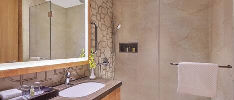 A bathroom with a marble sink, a large mirror, a shower with a glass door, and a towel rack.