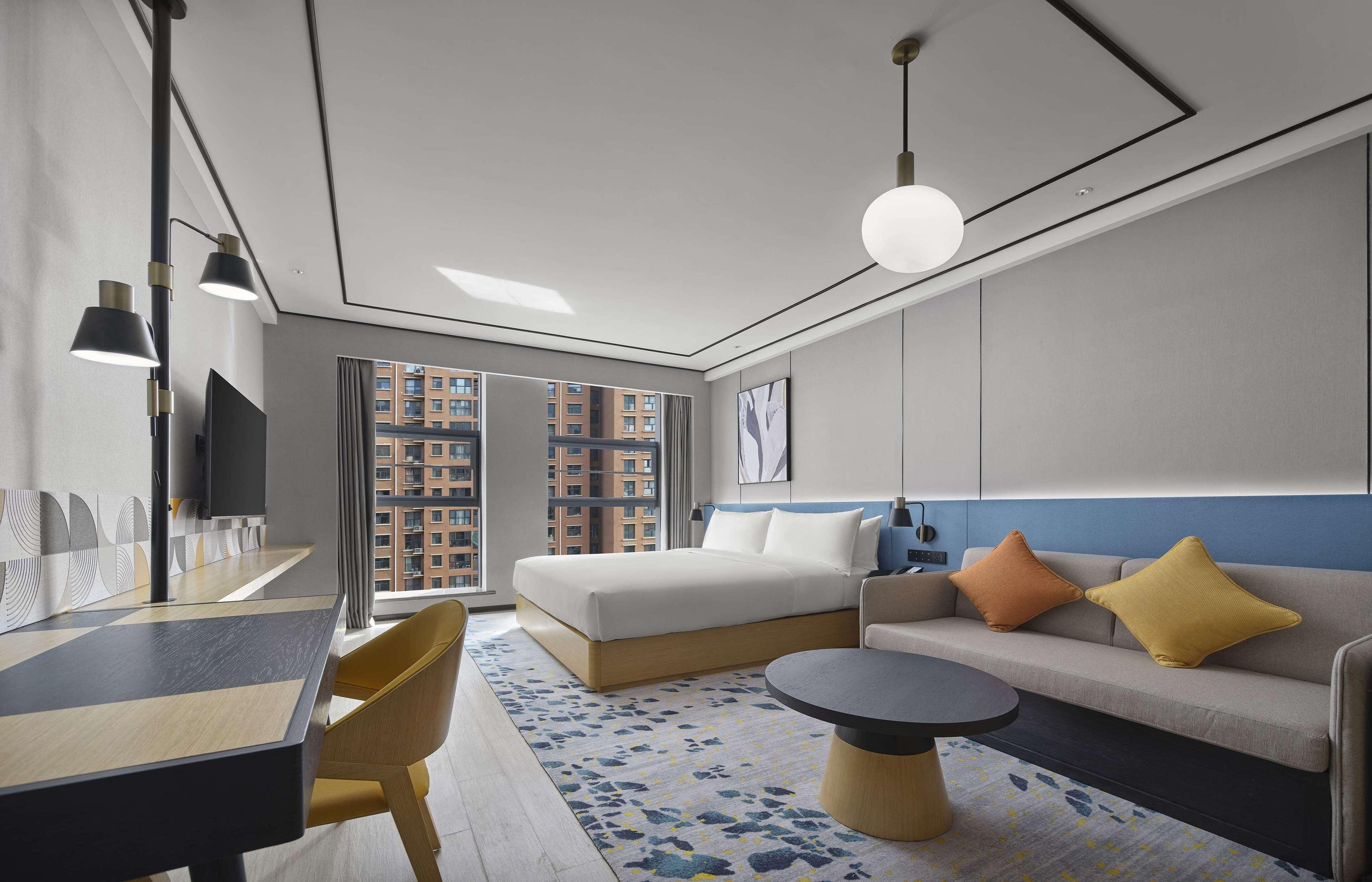 Una habitación de hotel moderna con una cama grande, un sofá, una mesa de comedor y un televisor.