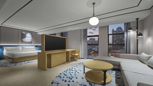 Habitación de hotel moderna con cama, sofá, televisión, escritorio y vista a la ciudad.