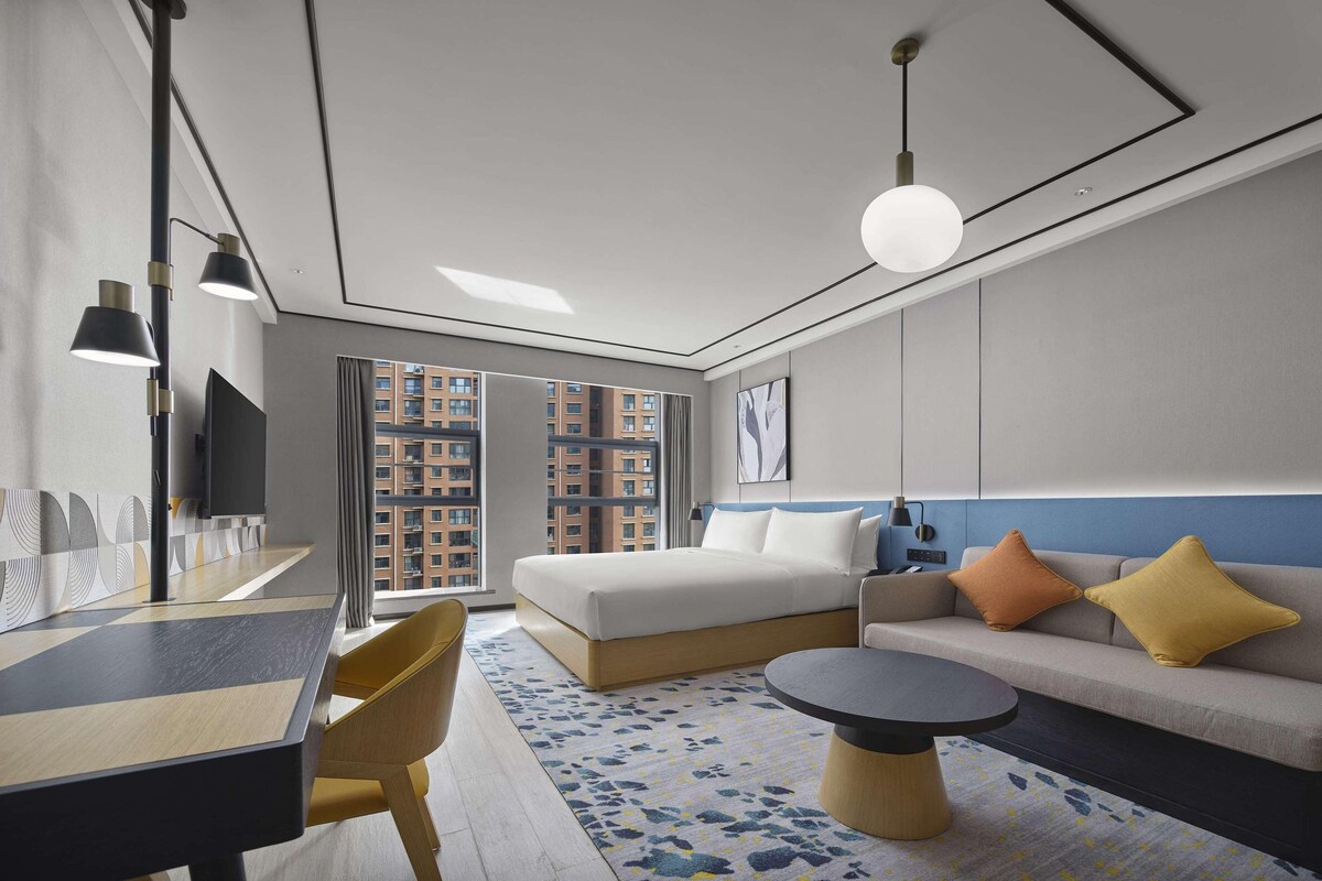Une chambre d’hôtel moderne équipée d’un grand lit, d’un canapé, d’une table à manger et d’un téléviseur.