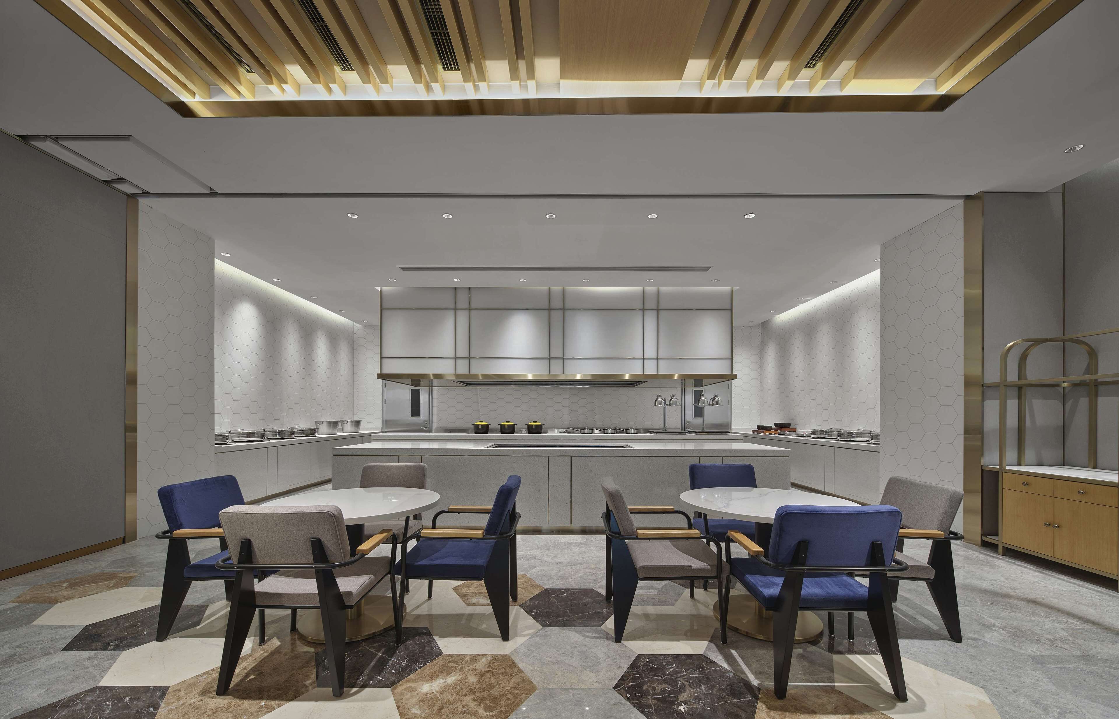 A modern kitchen with a central island, white cabinetry, and a hexagonal tile backsplash.