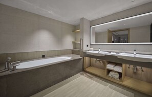 Un baño moderno con una bañera grande, dos lavamanos y un espejo amplio.