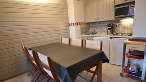Une cuisine compacte comprenant une table à manger, des chaises, un four à micro-ondes et un lave-vaisselle.