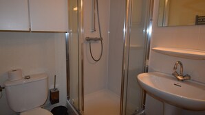 Une salle de bain avec une douche à parois de verre, des toilettes et un lavabo avec un miroir au-dessus.