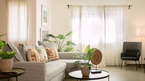 Ein modernes Wohnzimmer mit einer Couch, einem Couchtisch und Topfpflanzen.