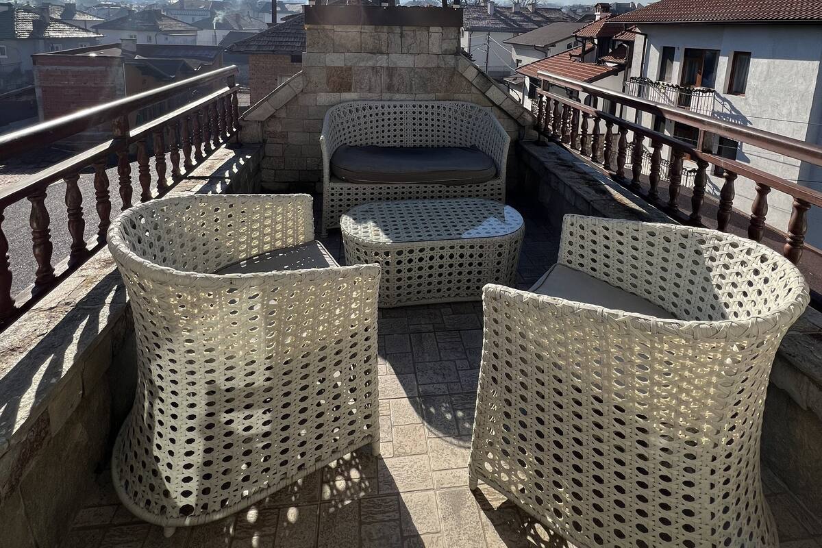 A terrace with wicker furniture, a stone structure, and a view of mountains.
