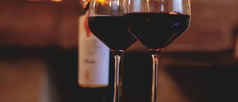 Two wine glasses on a table with a blurred background of a fireplace.