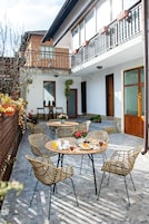 A courtyard with wicker chairs, a round table, and potted plants.