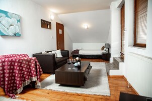 Una sala de estar moderna con una mesa de centro marrón oscuro, un mantel rojo estampado, un sofá y un cuadro de flores blancas en la pared.