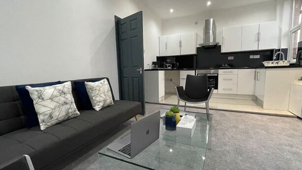 Ein modernes Wohnzimmer mit einer Couch, einem Glastisch und einem Laptop.