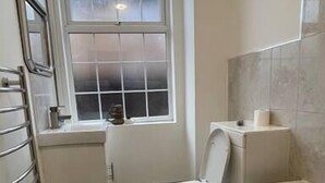 Ein kleines, kompaktes Badezimmer mit Toilette, Waschbecken und Badewanne.