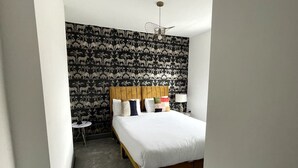 Ein Hotelzimmer mit einem Bett, einem runden Tisch und einer Wand mit ornamentalem Wandpapier.
